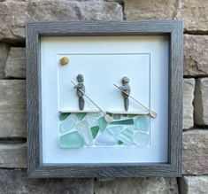 two birds sitting on top of a piece of sea glass in front of a stone wall