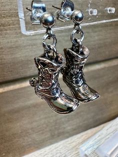 Add a touch of western flair to your accessories with these charming silver boot charm dangle earrings. Each intricately detailed boot charm swings gracefully from sturdy stainless steel earring posts, ensuring both style and durability. Perfect for country music fans or anyone looking to add a playful, rustic element to their jewelry collection, these earrings make a delightful fashion statement. Boot Charm, Western Gifts, Silver Boots, Rodeo Fashion, Kansas City Mo, Earring Posts, Cowboy Boot, Country Western, Music Fans