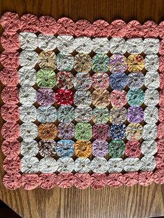 a pink and white quilt on top of a wooden table