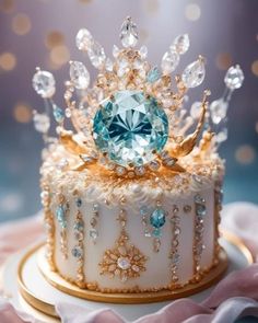 a white cake topped with a blue and gold crown sitting on top of a table