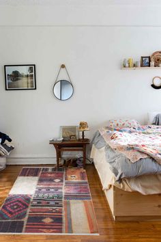 a bed room with a neatly made bed and a rug on the floor next to it