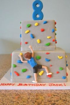 a birthday cake with a boy climbing on it and the number 8 on top is made out of frosting