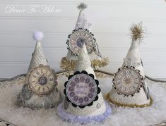 three small white christmas trees sitting on top of snow