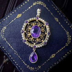 A glamorous antique Victorian pendant adorned with a large oval cut amethyst in the centre with a matching pear cut amethyst dropper below. Both have a deep, regal purple hue and are haloed by scrolling, filigree metalwork and a ring of alternating amethysts and seed pearls that chase around the border and up the bale.  Amethyst is the birthstone of February and is considered a stone of protection, clarity and tranquillity. Its deep violet colouring has been highly esteemed throughout history, a British Crown Jewels, Victorian Pendants, Victorian Design, Crown Jewels, Purple Hues, Pearl Pendant, Metal Working, Jewelry Necklace Pendant, Amethyst