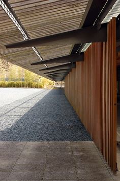 the walkway is lined with wooden slats and has an open roof over it to let in light