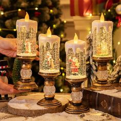 three lit candles sitting on top of a table next to a book and christmas tree