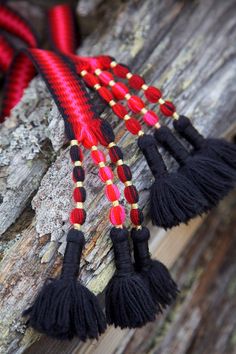 three tassels are hanging from a piece of wood with red and black beads