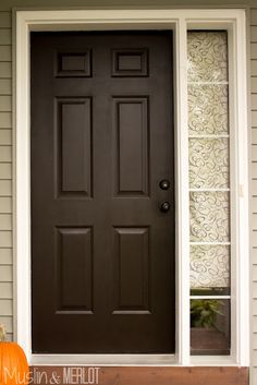 a black front door with two pumpkins on the steps