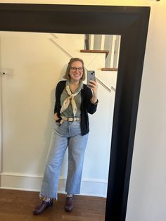 a woman standing in front of a mirror taking a selfie with her cell phone