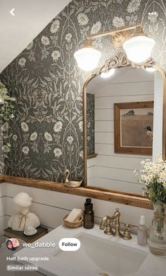 a bathroom sink under a large mirror next to a vase with flowers on top of it