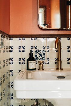 a white sink sitting under a bathroom mirror next to a wooden framed wall mounted mirror