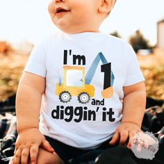 a baby sitting on the ground wearing a t - shirt that says i'm 1 and diggin'it