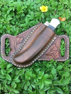 a knife sheath laying on top of some green plants