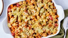 a casserole dish with meat and vegetables in it on a green napkin next to a fork