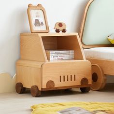 a wooden toy car with books in it on the floor next to a child's bed