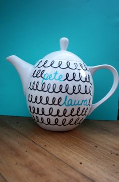 a ceramic teapot sitting on top of a wooden table next to a blue wall