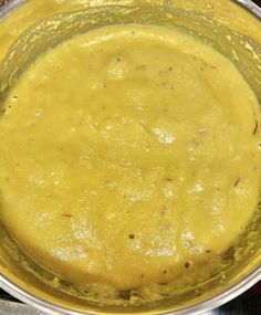 a metal bowl filled with yellow liquid on top of a stove