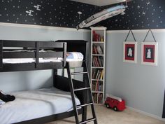 a bedroom with bunk beds, ladders and pictures on the wall above it is also a bookcase