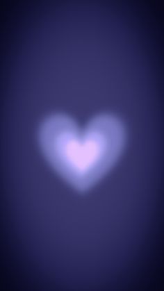 a blurry image of a white heart on a dark blue background with light coming from the center