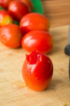 tomatoes on a cutting board next to an electric knife and pepper grinder in the background