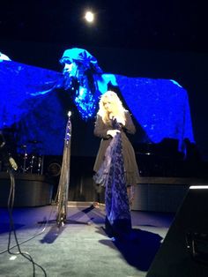 a woman standing in front of a stage with blue lights on her face and hands