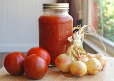 tomatoes and garlic sit on a table next to a jar of tomato sauce