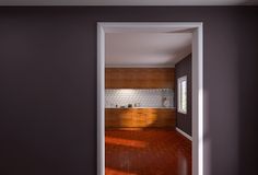 an open door leading into a kitchen with wood floors and cabinets on either side of the room