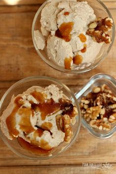 two bowls filled with ice cream and nuts on top of a wooden table next to each other