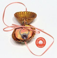 an orange and gold shell with a pink ribbon around it