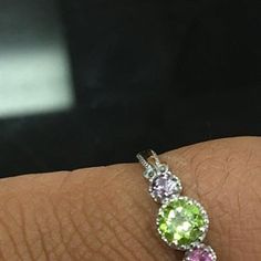 a woman's hand with three different colored stones on it and an engagement ring