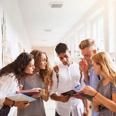 group of people standing around each other looking at something on a clipboard in an office