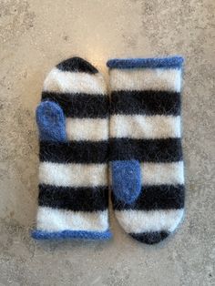 a pair of black and white striped mittens laying on top of a cement floor