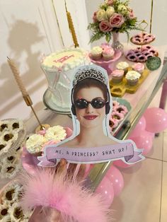 a table topped with cakes and cupcakes covered in pink frosting next to a cake