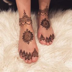 a woman's feet with henna tattoos on them