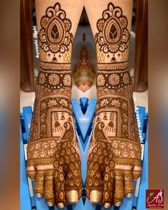 the legs and feet of a woman with henna tattoos on their hands, showing intricate designs