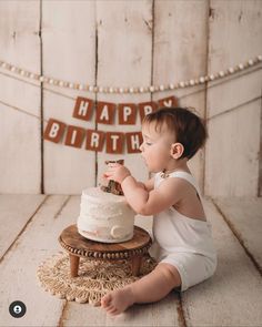 a baby sitting in front of a birthday cake