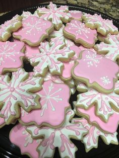 some pink and white decorated cookies on a black plate