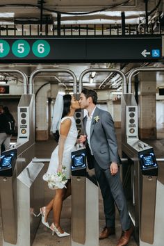 a newly married couple kissing in front of an airport check - in kiosk