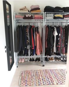 an organized closet with clothes, shoes and rugs on the floor in front of it