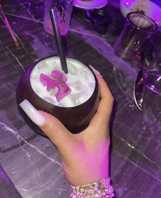 a woman's hand holding a drink with pink decorations on it