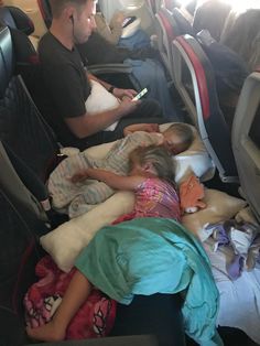 two children sleeping on an airplane with their parents