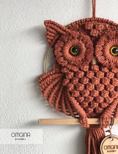 an owl ornament hanging on a wall with a wooden hanger attached to it