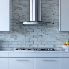 a kitchen with white cabinets and marble tile backsplash, stainless steel range hood over the stove