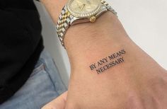 a person with a wrist tattoo that says by any means necessary on the wrist,