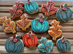 some decorated cookies are sitting on a wooden table with leaves and pumpkins in the background