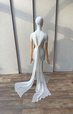 a mannequin wearing a white dress with sheer fabric draped over it's back