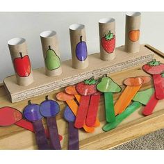 a wooden table topped with lots of cut out fruit and vegetables next to cups on top of each other