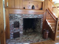 an old brick fireplace in the middle of a room with wooden stairs and railings