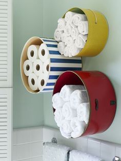 two tin canisters with toilet paper in them hanging on the wall above a sink