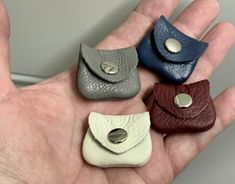 four small leather purses are in the palm of someone's hand with their fingers